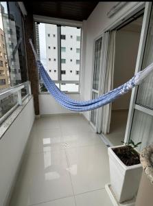 a hammock in the middle of a room with windows at Apartamento 01suite e um quarto in Balneário Camboriú
