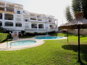 a large building with a swimming pool and an umbrella at Valparaiso Apartment Burriana Beach in Nerja