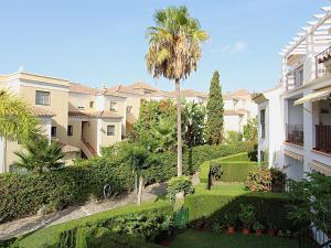 an apartment building with a palm tree and a garden at Valparaiso Apartment Burriana Beach in Nerja