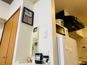 a kitchen with a refrigerator and a phone on a wall at Shinjuku house 2 in Tokyo