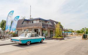 a blue and white car parked in front of a building at Glamping Betuwestrand in Beesd