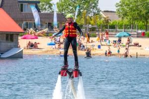 a young girl is standing on a water board in the water at Glamping Betuwestrand in Beesd