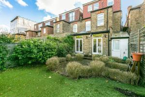 einen Garten vor einem großen Backsteingebäude in der Unterkunft 5-Bed Family Retreat in Chiswick in London