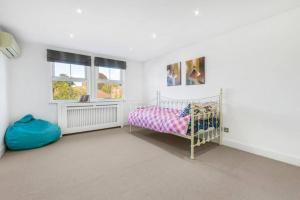 ein weißes Schlafzimmer mit einem Bett und einem Fenster in der Unterkunft 5-Bed Family Retreat in Chiswick in London