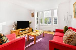ein Wohnzimmer mit roten Möbeln und einem Flachbild-TV in der Unterkunft 5-Bed Family Retreat in Chiswick in London