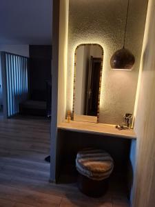 a bathroom with a vanity with a mirror and a stool at New Grey Apartament in Reghin