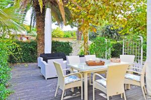 patio ze stołem, krzesłami i drzewem w obiekcie Holiday Apartments Fiumetto w mieście Marina di Pietrasanta