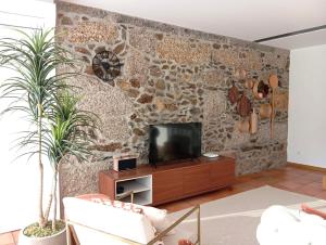 a living room with a stone wall with a television at Dalpendre - Turismo em espaço rural in Felgueiras