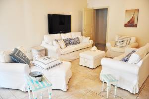 salon z białymi kanapami i telewizorem z płaskim ekranem w obiekcie Holiday Apartments Fiumetto w mieście Marina di Pietrasanta