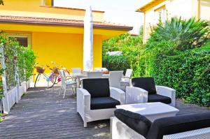 patio z krzesłami i stołami oraz żółty dom w obiekcie Holiday Apartments Fiumetto w mieście Marina di Pietrasanta