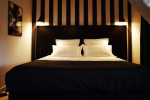 uma cama com cabeceira preta e almofadas brancas em Hotel des Carmes em Aurillac