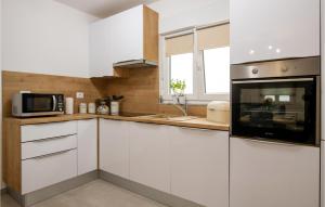 a kitchen with white cabinets and a microwave at Gorgeous Home In Radeki Glavica in Loborika