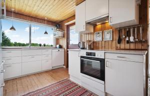a kitchen with white cabinets and a large window at Holiday Home Harresbæk Iii in Skovby