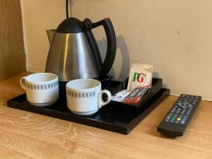 a tea kettle and two cups and a remote control at Alumhurst Hotel in Blackpool