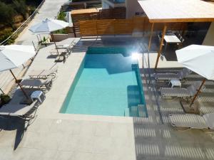 une piscine avec chaises et parasols dans l'établissement Louloudi Hills Villa 3, à Koskinou