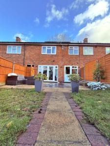 a brick house with two potted plants in front of it at Three bedroom house in Harlow
