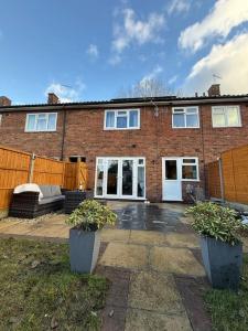 a brick house with two potted plants in front of it at Three bedroom house in Harlow