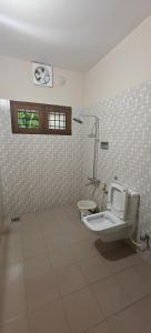 a bathroom with a toilet and a tiled wall at Alite Posh 4 BHK Villa in Thrissur Town in Trichūr