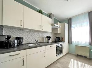 a kitchen with white cabinets and a sink and a window at Ferienhaus DolceVita in Walkenried