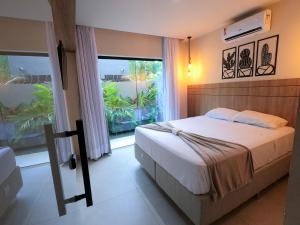 a bedroom with a bed and a large window at LAWAKE House pipa Studios e apartamentos nomads in Pipa
