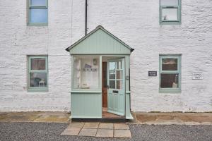 a white building with a green door and windows at Hexham Cottage by Coast & Country Stays in Seahouses