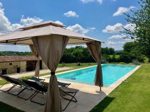 a large umbrella and chairs next to a swimming pool at Chambres d'hôtes au Château de Gandillac in Saint-Martial-Viveyrol