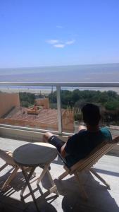 a man sitting on a chair looking out at the ocean at Rest Departamento con vista al mar in San Bernardo