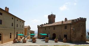 an old stone building with green umbrellas in a courtyard at Tenuta di Casaglia in Podere Colombaie