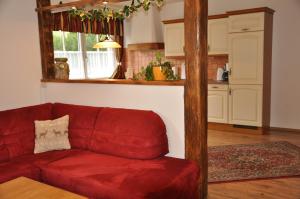a red couch in a living room with a kitchen at Appartementhaus Eberlhof in Pruggern