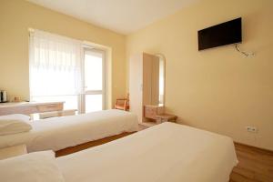 a bedroom with two beds and a television on the wall at LUNA Marijampole in Marijampolė +27 photos