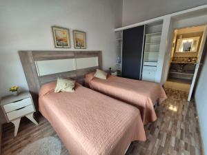 twee bedden in een kamer met roze lakens erop bij Departamento Las Calandrias in Cipolletti