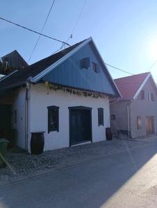 a white building with a black roof on a street at Vinska kuća na vinskoj cesti Zmajevac in Zmajevac