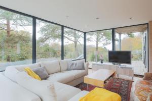 een woonkamer met een witte bank en een tv bij Entre Terre Et Mer in Locquirec