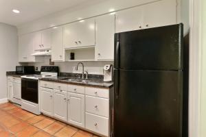 Una cocina con gabinetes blancos y un refrigerador negro. en 17 E Jones Garden, en Savannah