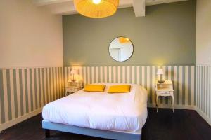 una camera da letto con un letto con due cuscini gialli e uno specchio di Grande maison de charme avec piscine 11 pers a Charras
