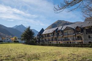 a large building with mountains in the background at Le Village des Thermes in Vignec