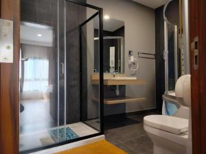 a bathroom with a shower and a toilet and a sink at Flora Hotel Ivato International Airport in Antananarivo +68 photos