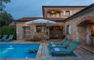 a house with a swimming pool with chairs and an umbrella at Villa Novel in Višnjan
