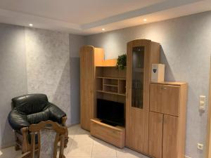 a living room with a large wooden cabinet and a chair at Ferienwohnung Hammesdammer-Land in Lastrup