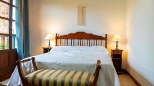 a bedroom with a bed and two lamps and a chair at Casa del Sur El Collau in Porrúa