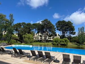 a pool with chairs and a house in the background at Green Park - Studio in Punta del Este