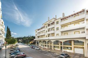 a large white building with cars parked in a parking lot at 212 Aurora sol - CASINHA DO SOL in Praia do Carvoeiro