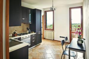 una cocina con armarios negros y una mesa con sillas en Giardino Ferrari, en Verona