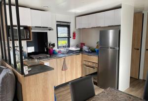 a kitchen with a stainless steel refrigerator and wooden cabinets at Location Mobilhome Bahiana 8 personnes Camping 4 étoiles La Réserve Gastes in Gastes