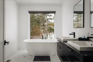 a white bathroom with a large tub and two sinks at Le Nordet - SPA & Play room in Saint Come