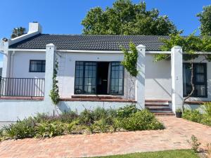 a white house with a brick driveway at Chasselas Self Catering in Cape Town