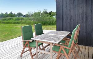 a wooden table and two green chairs on a deck at Holiday Home Kuskevej Jerup in Jerup