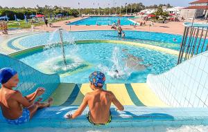 two young boys sitting in a swimming pool at V4 Zona Verde in Isola Albarella +48 photos