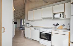 a kitchen with white cabinets and a stove top oven at Amazing Home In Ringkøbing With Sauna in Ringkøbing
