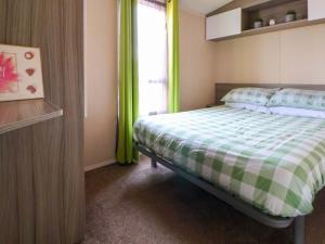 a bedroom with a bed with green curtains and a window at Marina in Rhyl